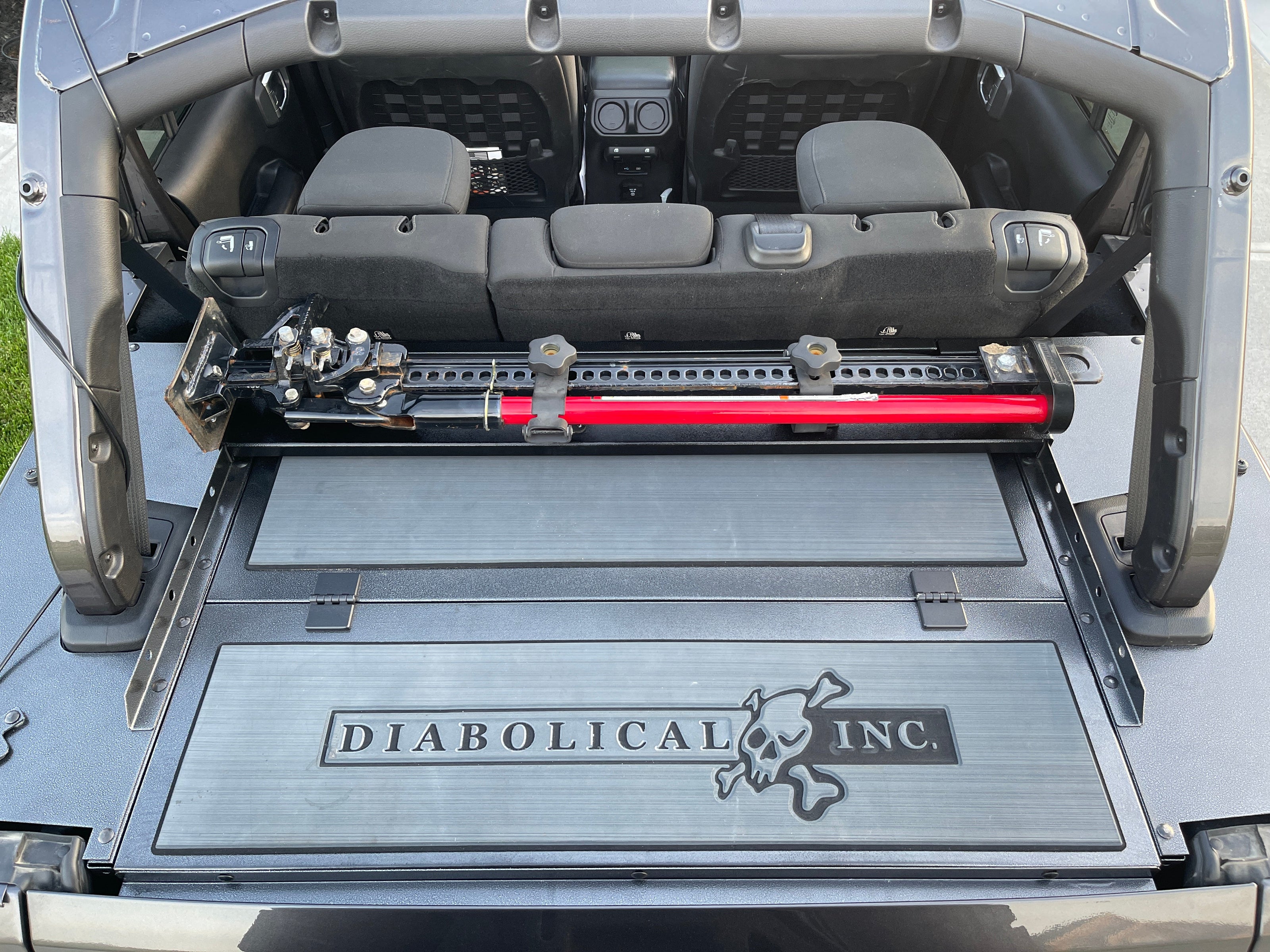 Image of a Jeep Wrangler JKU with a Diabolical, Inc. Slipstream security enclosure and foam deck pads with the Rail Rack accessory mount installed with a HiLift Jack.