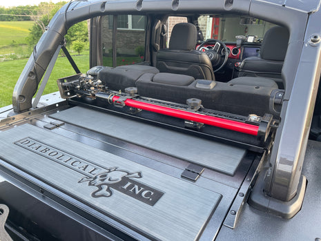 Image of a Jeep Wrangler JKU with a Diabolical, Inc. Slipstream security enclosure and foam deck pads with the Rail Rack accessory mount installed with a HiLift Jack.